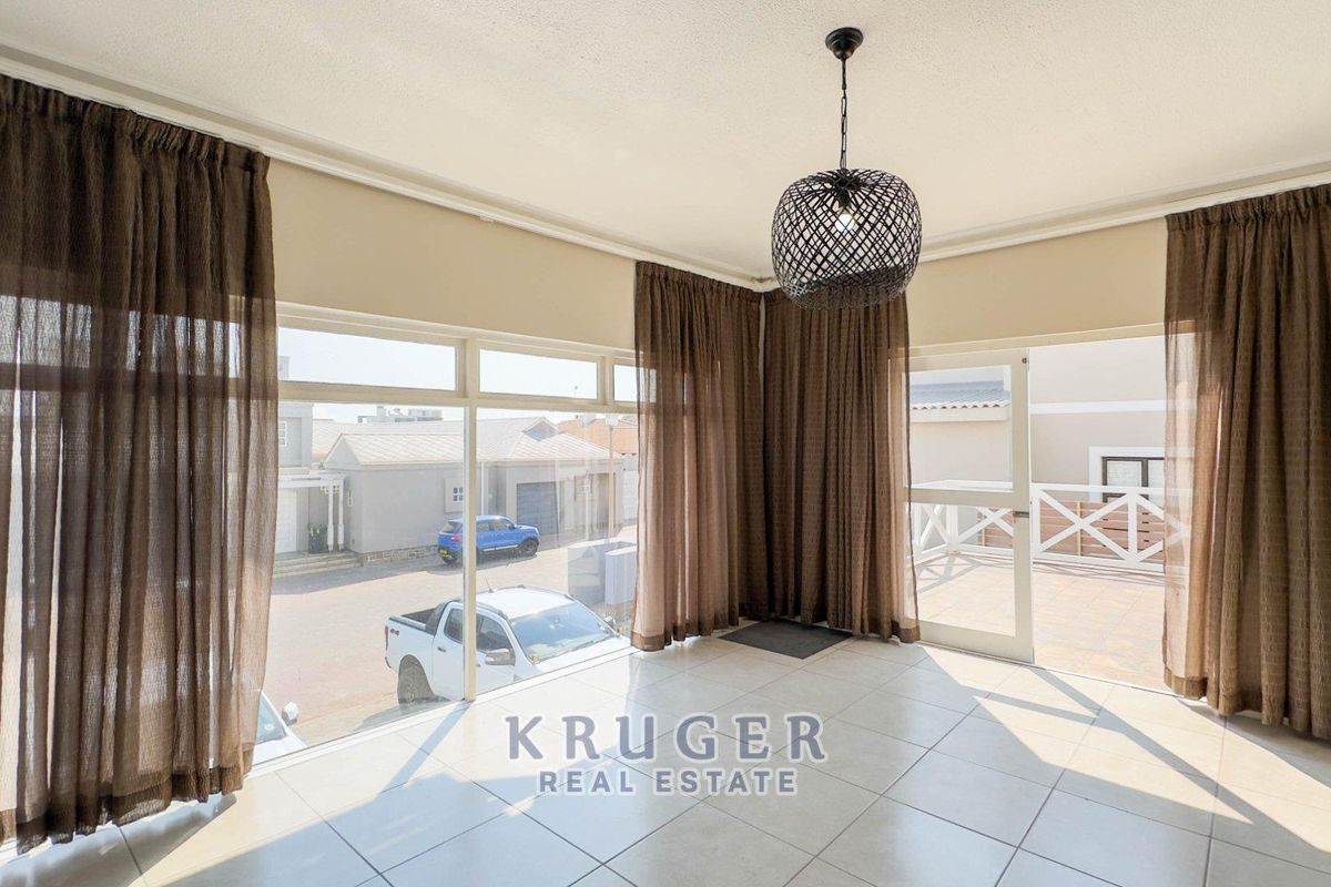 Bright and spacious living area featuring large windows, tiled flooring, and direct access to an outdoor patio space.