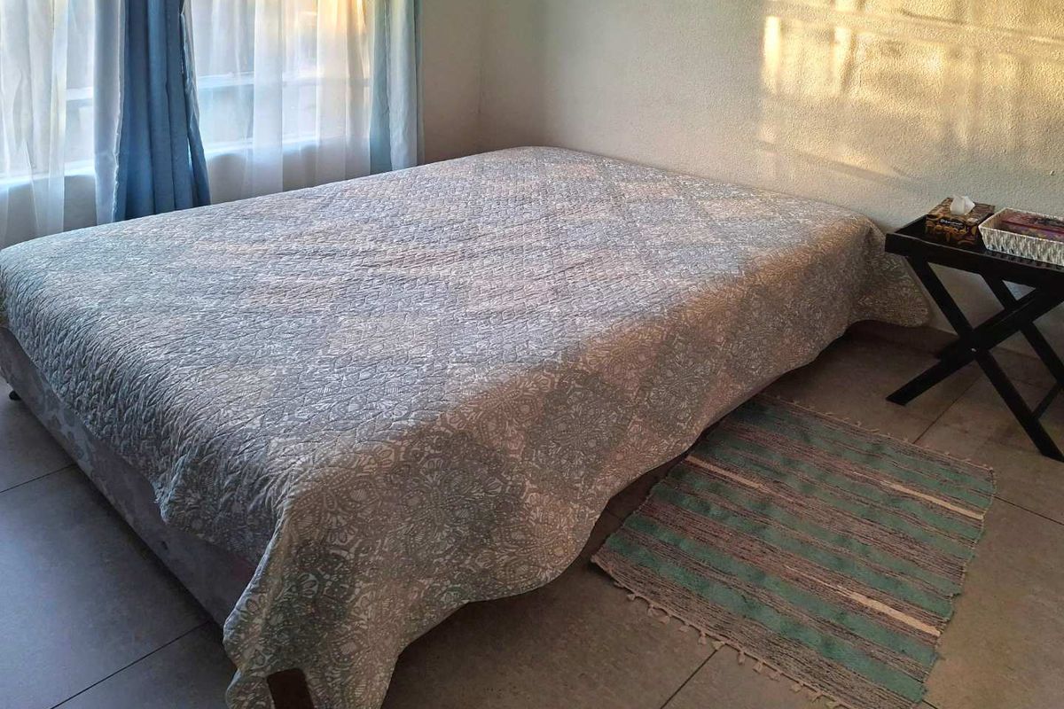 A bedroom featuring neutral tiled flooring and natural light from the window.