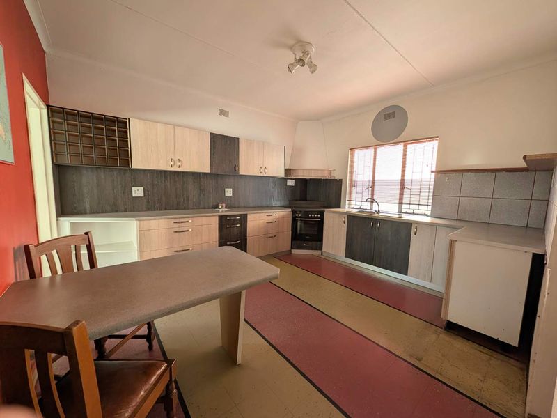 A functional kitchen featuring built-in cabinetry, a built-in oven with extractor fan, and a stainless steel sink with tiled splashback.