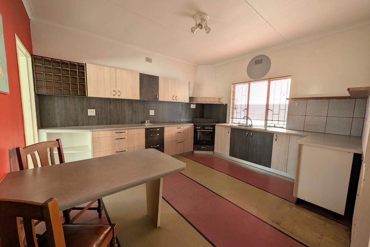 A functional kitchen featuring built-in cabinetry, a built-in oven with extractor fan, and a stainless steel sink with tiled splashback.