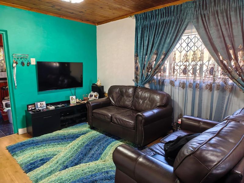 A living room featuring a timber ceiling, laminate flooring, and a window fitted with a security gate.
