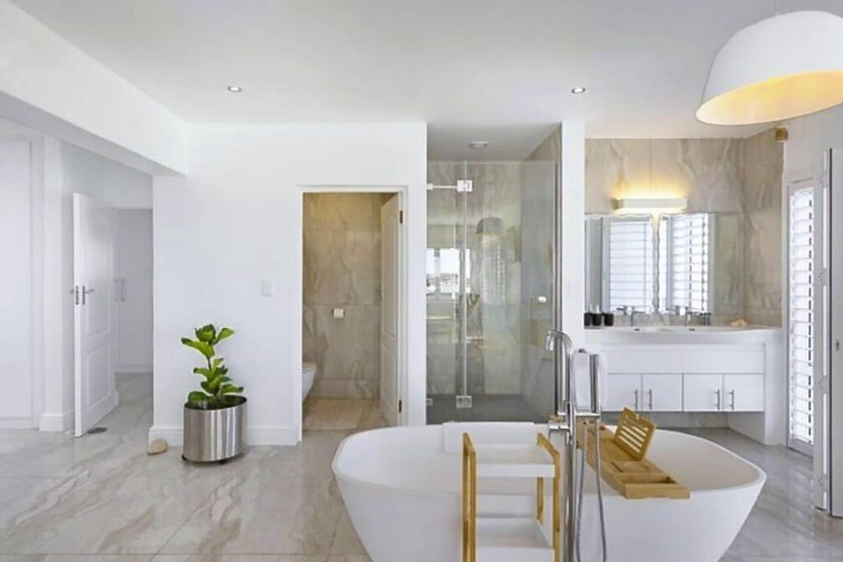 Modern, spacious bathroom featuring a freestanding bathtub, double vanity with integrated storage, glass-enclosed shower, and neutral marble-look floor tiles.