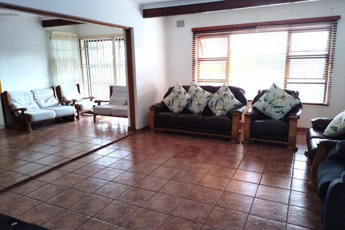 Spacious living area featuring ceramic tile flooring, exposed timber ceiling beams, and large windows with venetian blinds, offering a bright and open layout.