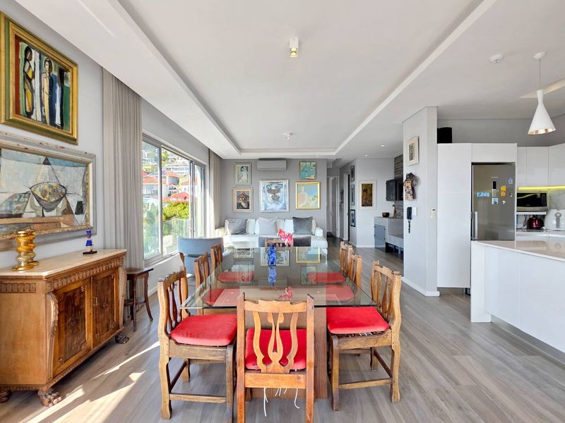 Spacious open-plan living and dining area featuring modern laminate flooring, recessed ceiling lighting, and a sleek integrated kitchen with ample cabinetry.