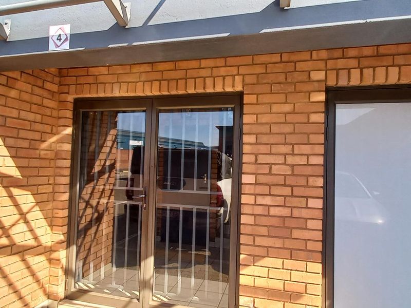 Exterior view of the industrial unit entrance featuring face brick facade, metal security gates, and a covered entryway.
