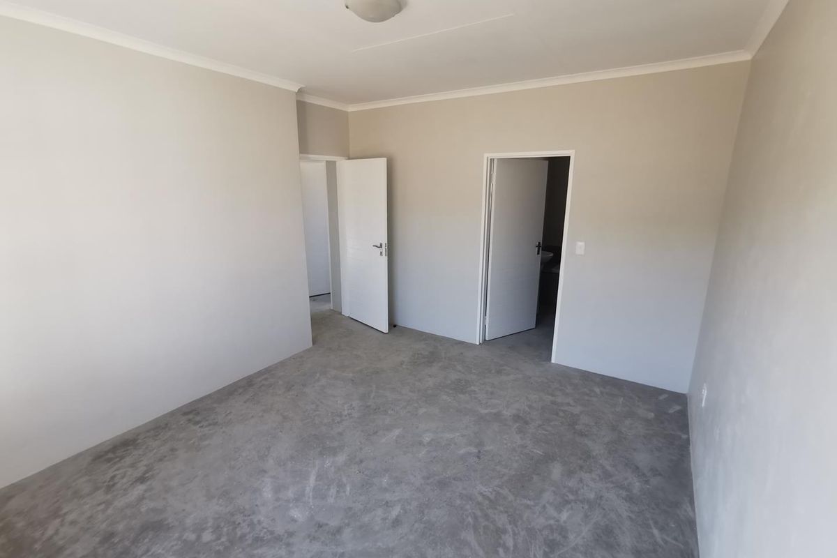 A vacant bedroom featuring neutral painted walls, a ceiling light fixture, and unfinished concrete flooring, ready for final floor covering installation.