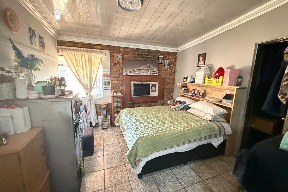 A bedroom featuring exposed brickwork, tiled flooring, and a timber ceiling, offering a rustic aesthetic with potential for modernization.