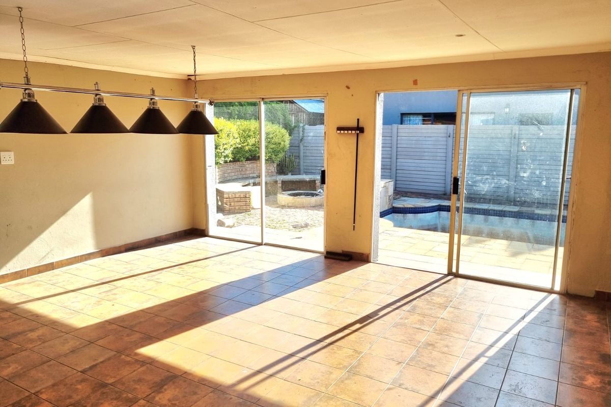 Spacious, sunlit living area featuring tiled flooring and dual sliding glass doors providing direct access to the outdoor pool and patio area.