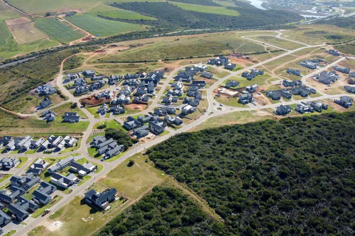 Aerial view of a residential estate development featuring modern homes, paved road infrastructure, and surrounding natural landscape.