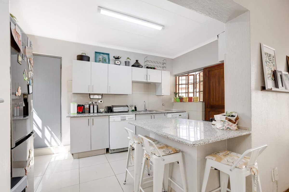 A functional kitchen featuring white cabinetry, granite countertops, a breakfast bar, and tiled flooring, offering a clean and practical workspace.