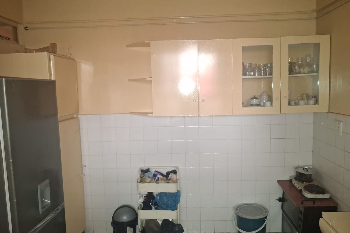 A functional kitchen space featuring tiled backsplash, built-in cabinetry with glass-fronted upper units, and tiled flooring, offering potential for modernization.