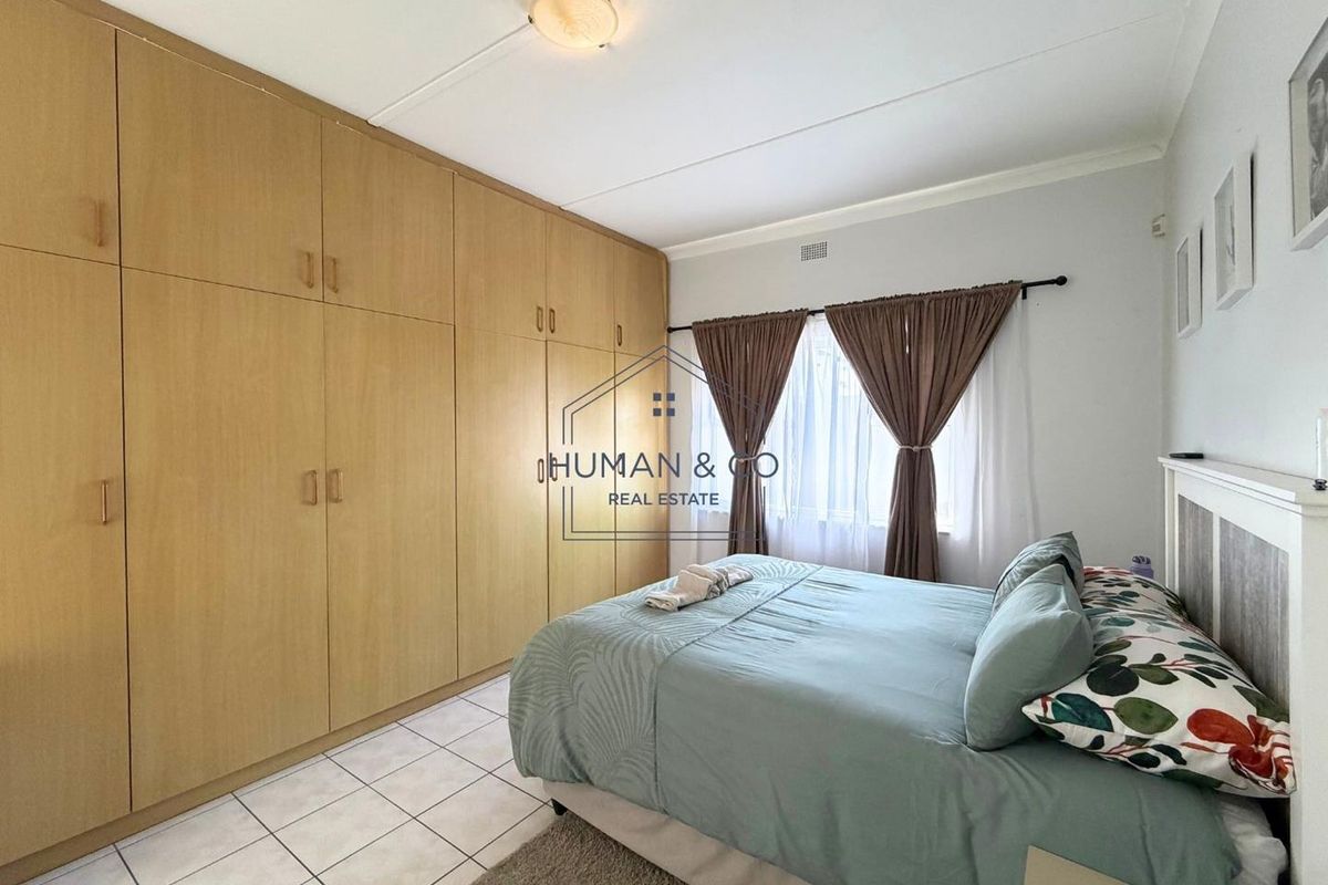 A bedroom featuring extensive built-in wooden cabinetry, tiled flooring, and a window with curtain rods.