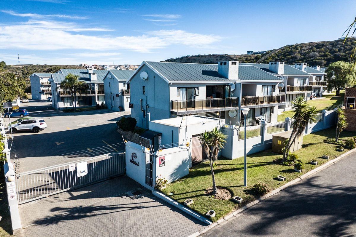 Aerial view of a modern apartment complex featuring metal roofing, private balconies, secure gated access, and well-maintained landscaped grounds.