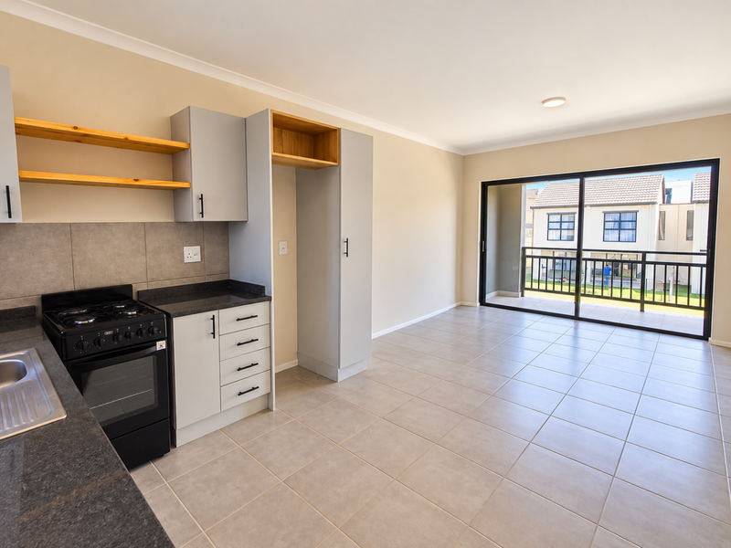 Modern open-plan kitchen and living area featuring neutral cabinetry, stone countertops, tiled floors, and direct access to a private balcony.
