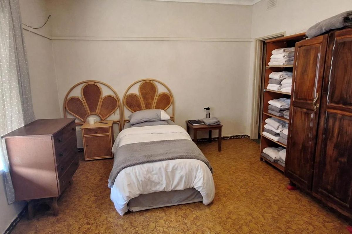 A bedroom featuring a built-in wardrobe, ceiling coving, and visible signs of ceiling water damage and floor wear requiring maintenance.