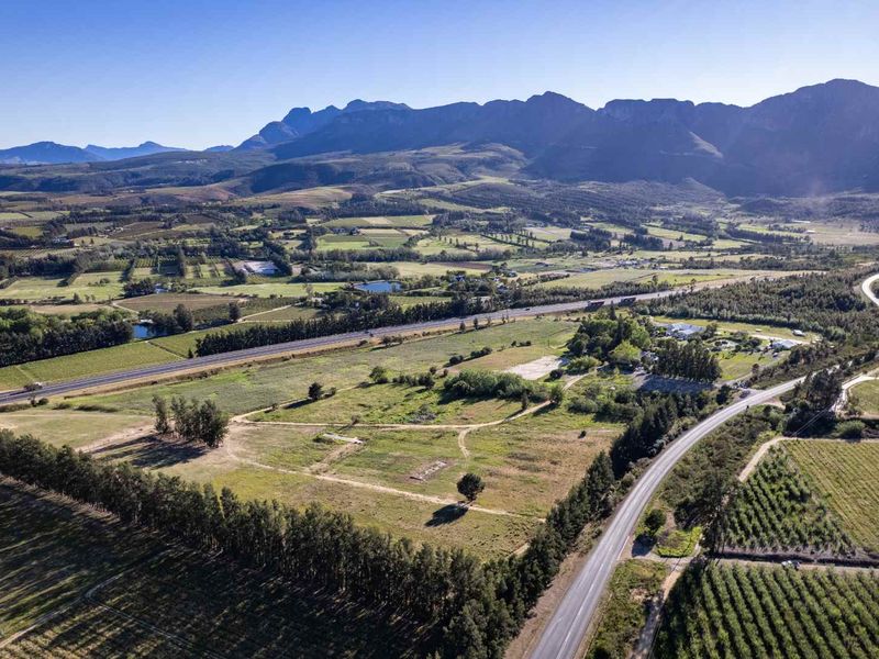 An expansive aerial view of the farm property, showcasing the surrounding agricultural landscape, mountain backdrop, and access roads.