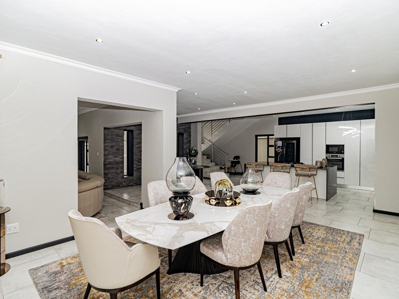Spacious open-plan dining area flowing into a modern kitchen with sleek cabinetry, integrated appliances, and tiled flooring throughout.
