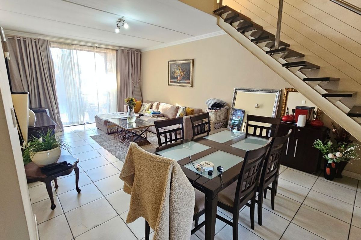 Open-plan living and dining area featuring tiled flooring, a staircase, and large sliding glass doors providing access to the outdoor space.