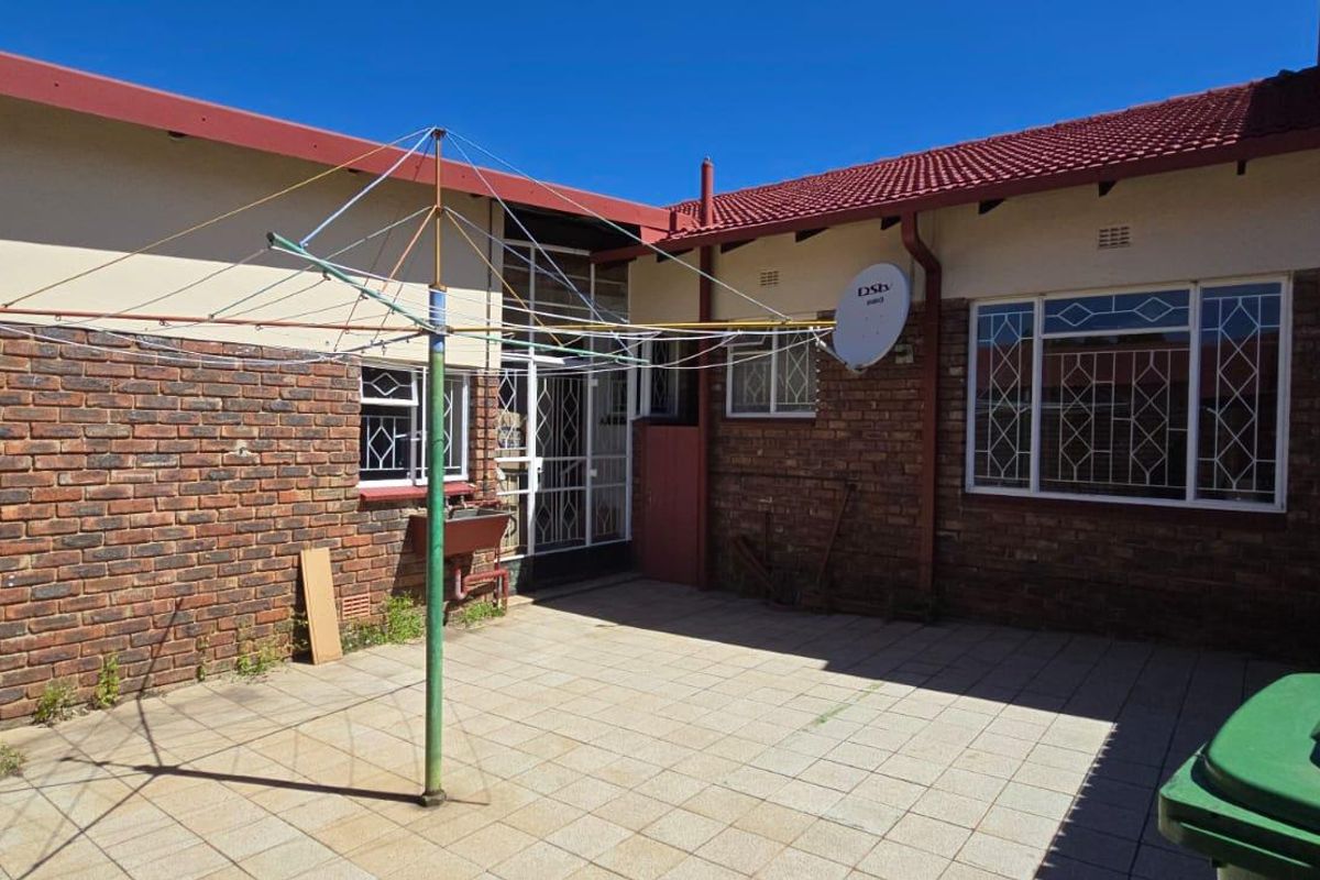 A paved rear courtyard area featuring face-brick walls, security gates, and a washing line, providing a functional outdoor space for the townhouse.