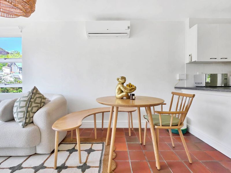 Open-plan living and kitchen area featuring terracotta floor tiles, white cabinetry, and a wall-mounted split-system air conditioner.