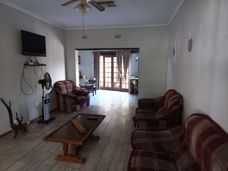 Spacious living room featuring tiled flooring, a ceiling fan, and direct access to an outdoor area through wooden french doors.