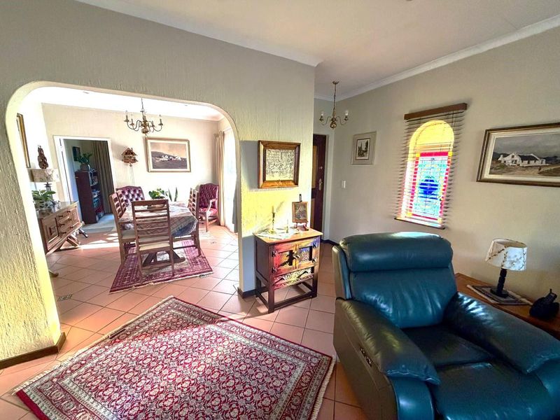 Open plan living and dining area featuring terracotta floor tiles, a distinctive arched transition, and a decorative stained glass window.