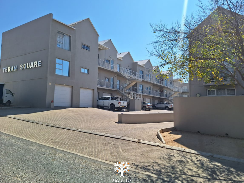 Exterior view of Terah Square apartment complex featuring paved driveway, garage access, and multi-level residential units with external staircases.