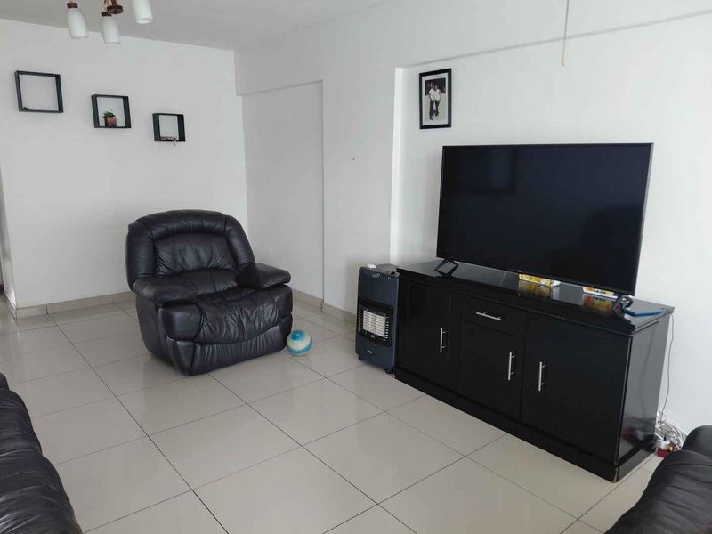 A living room featuring neutral tiled flooring and a built-in wall niche, providing a functional and clean space for relaxation.