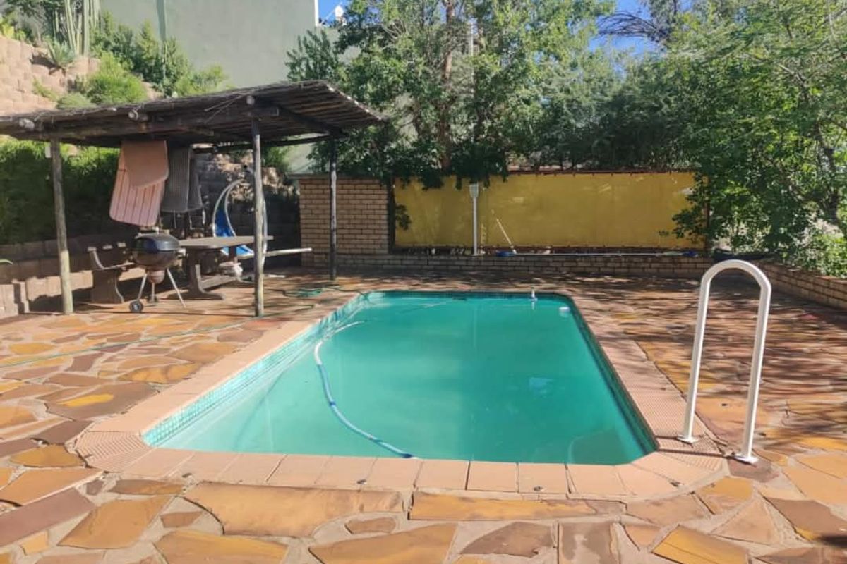 Outdoor pool area featuring a swimming pool, paved surround, and a covered patio structure for shaded relaxation.
