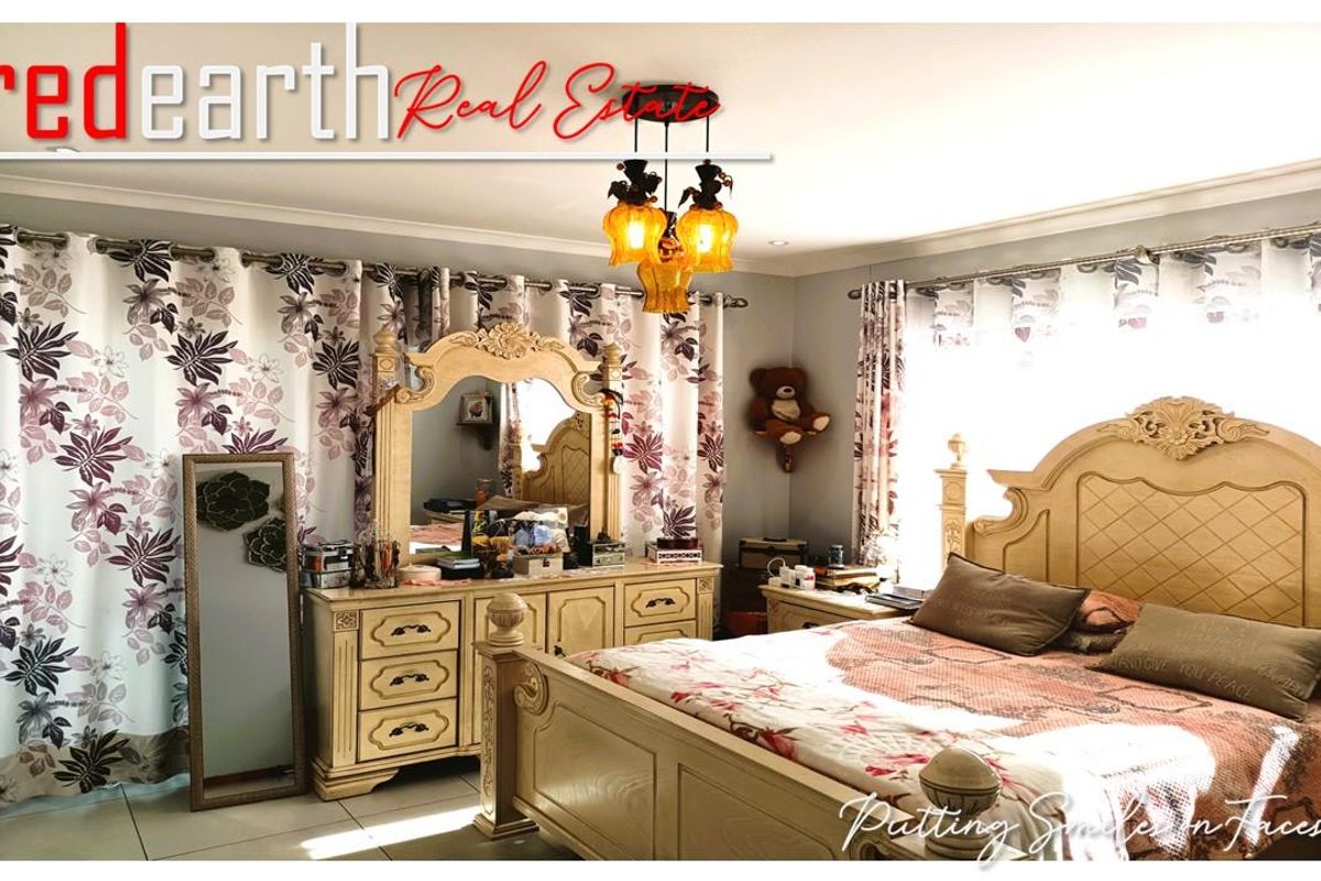 A spacious bedroom featuring tiled flooring, large windows with decorative curtains, and recessed ceiling lighting.