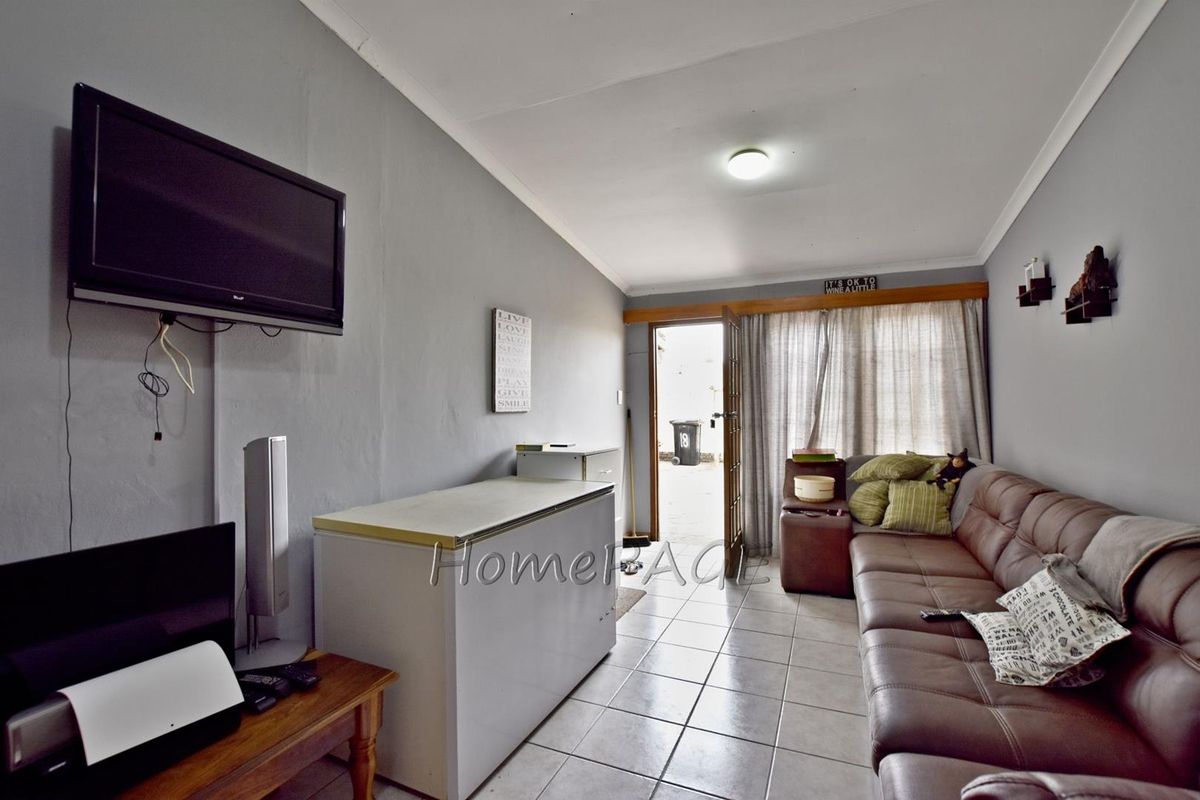 A living room featuring tiled flooring and direct access to the exterior, providing a functional space with potential for cosmetic updates.