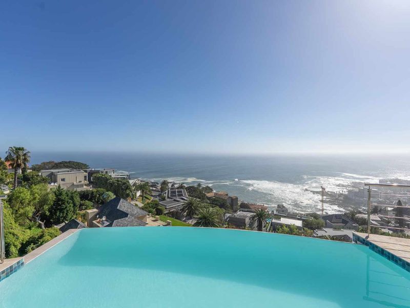Stunning infinity edge swimming pool overlooking the ocean and coastal landscape, featuring modern stainless steel balustrades.