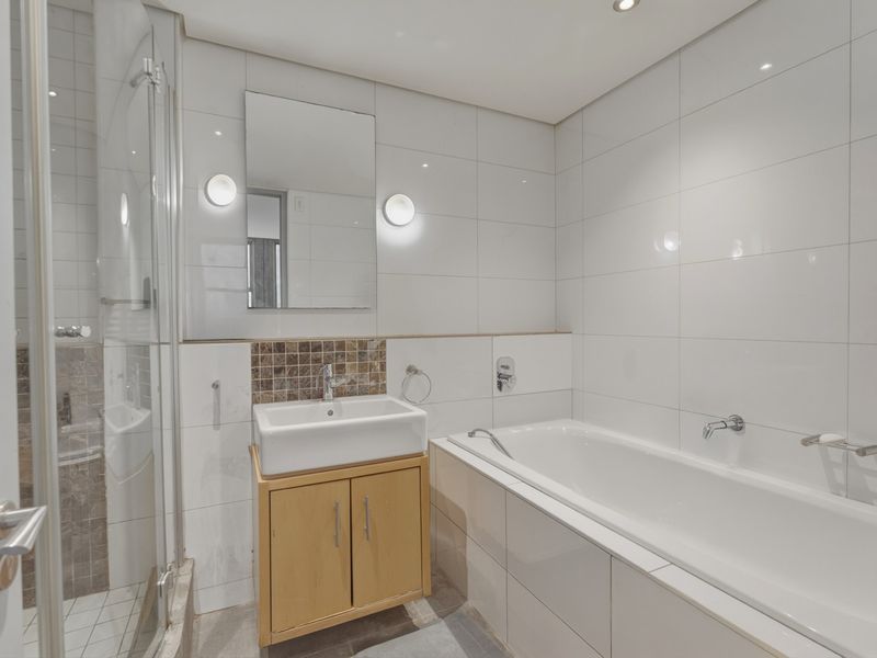 A clean, modern bathroom featuring a built-in vanity, a separate shower enclosure, and a bathtub with white wall tiling.