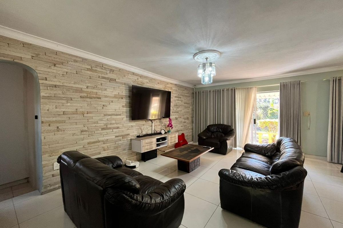 Spacious living room featuring a textured stacked stone feature wall, neutral tiled flooring, and direct access to the outdoor area through sliding glass doors.