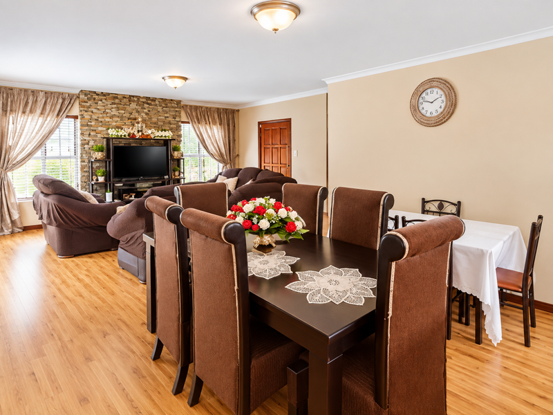 Spacious open-plan living and dining area featuring laminate flooring, a stone feature wall, and neutral wall finishes.