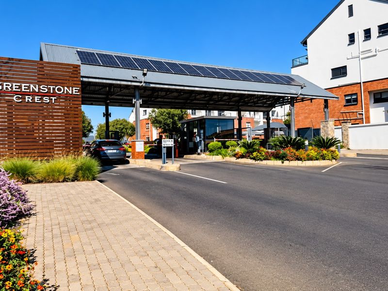 The main entrance and security gatehouse of Greenstone Crest, featuring a modern structure with solar panels and well-maintained landscaped gardens.