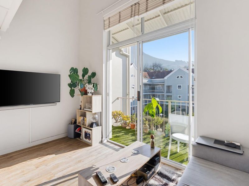 Bright living room featuring laminate flooring and large sliding glass doors that provide direct access to a private balcony with scenic views.