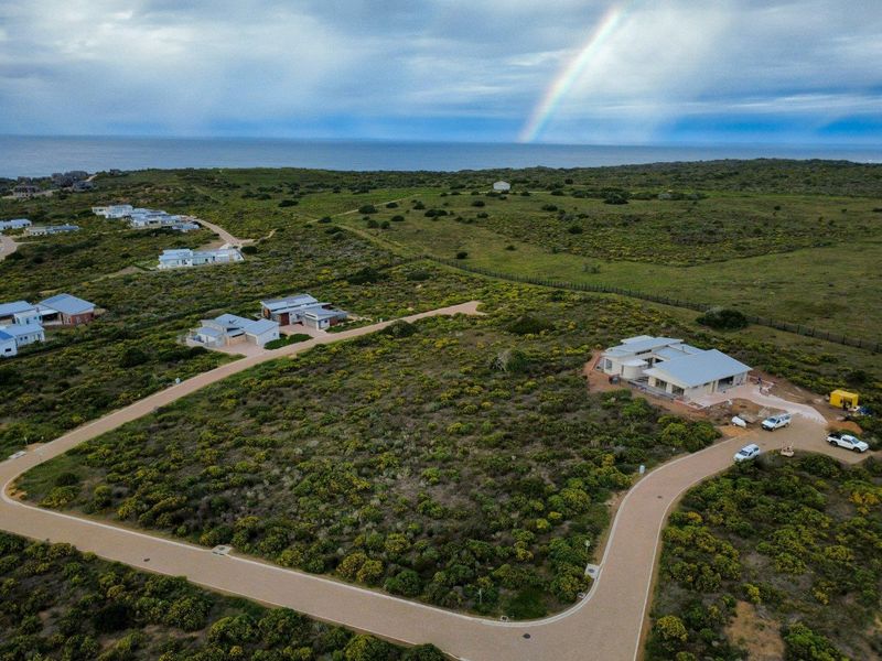 Aerial view of a residential plot in a coastal estate, featuring established road infrastructure and surrounding natural vegetation.
