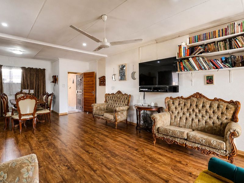 Spacious open-plan living and dining area featuring laminate flooring, a ceiling fan, and built-in wall shelving.