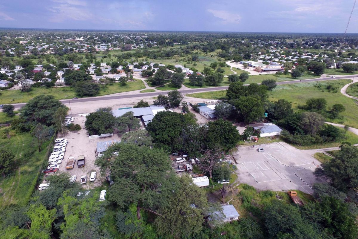 Aerial view of an industrial property featuring multiple structures, paved and unpaved parking areas, and surrounding green space.