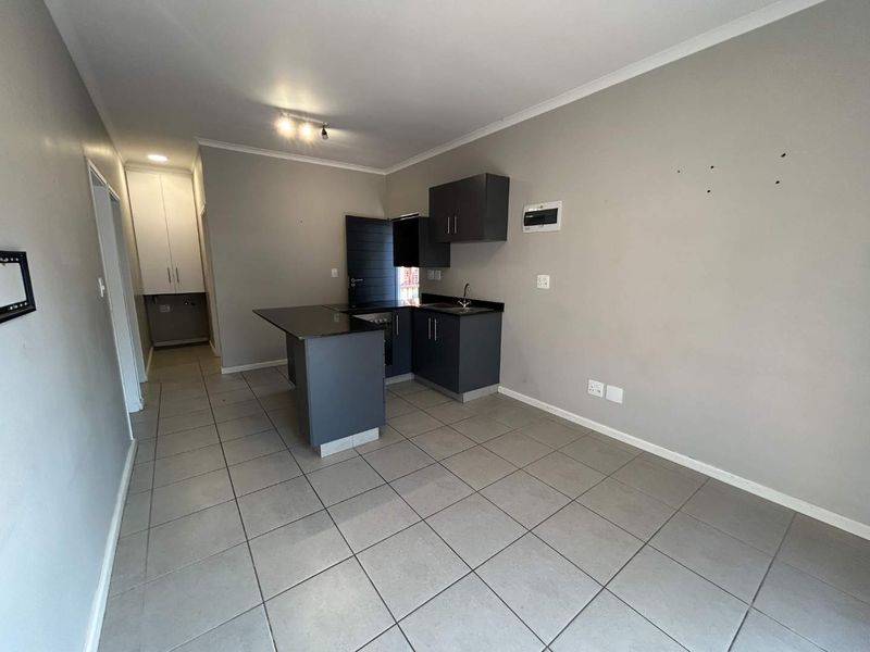 Compact kitchen featuring dark grey cabinetry, granite countertops, and tiled flooring. The space is currently vacant and ready for personalization.
