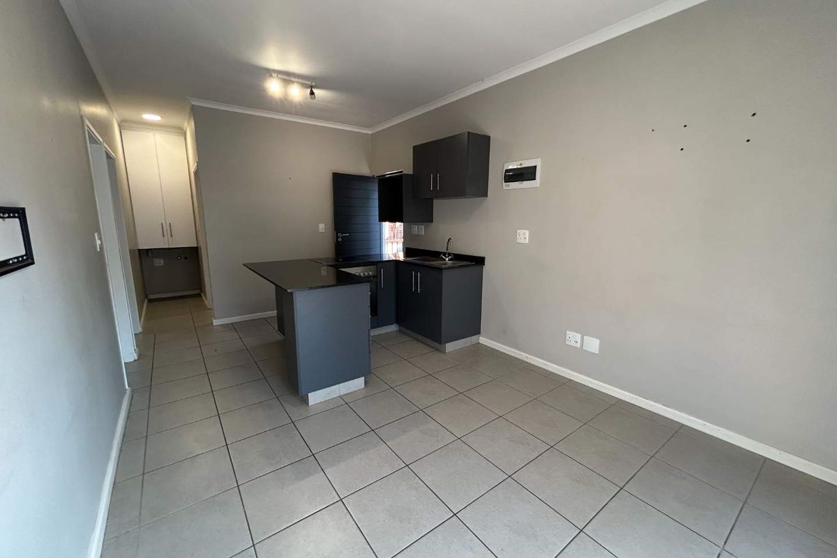 Compact kitchen featuring dark grey cabinetry, granite countertops, and tiled flooring. The space is currently vacant and ready for personalization.