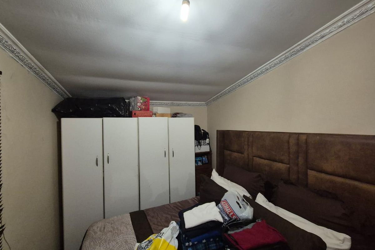 A bedroom featuring a built-in wardrobe and decorative ceiling cornicing, requiring cosmetic updates to the ceiling and general finishes.