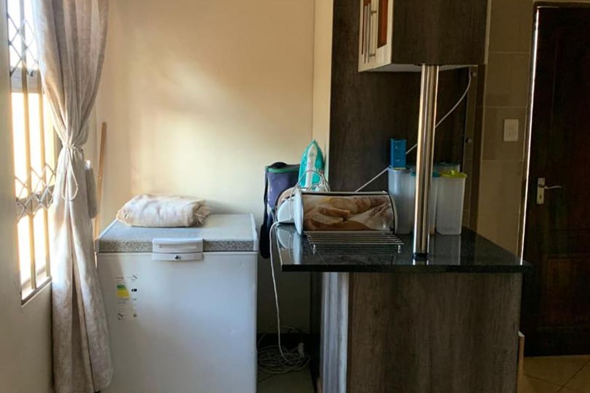 A functional kitchen area featuring dark wood-look cabinetry, a granite countertop, and tiled flooring, providing a compact and practical workspace.