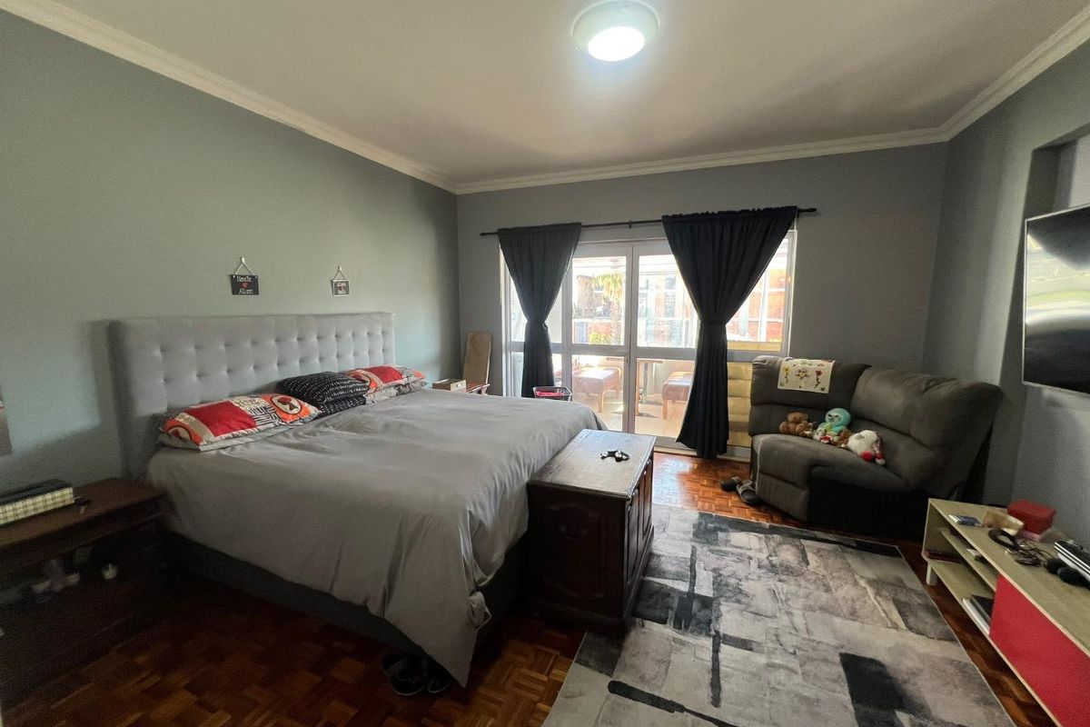 Spacious bedroom featuring classic parquet flooring, coved ceilings, and a sliding glass door providing access to an outdoor balcony area.
