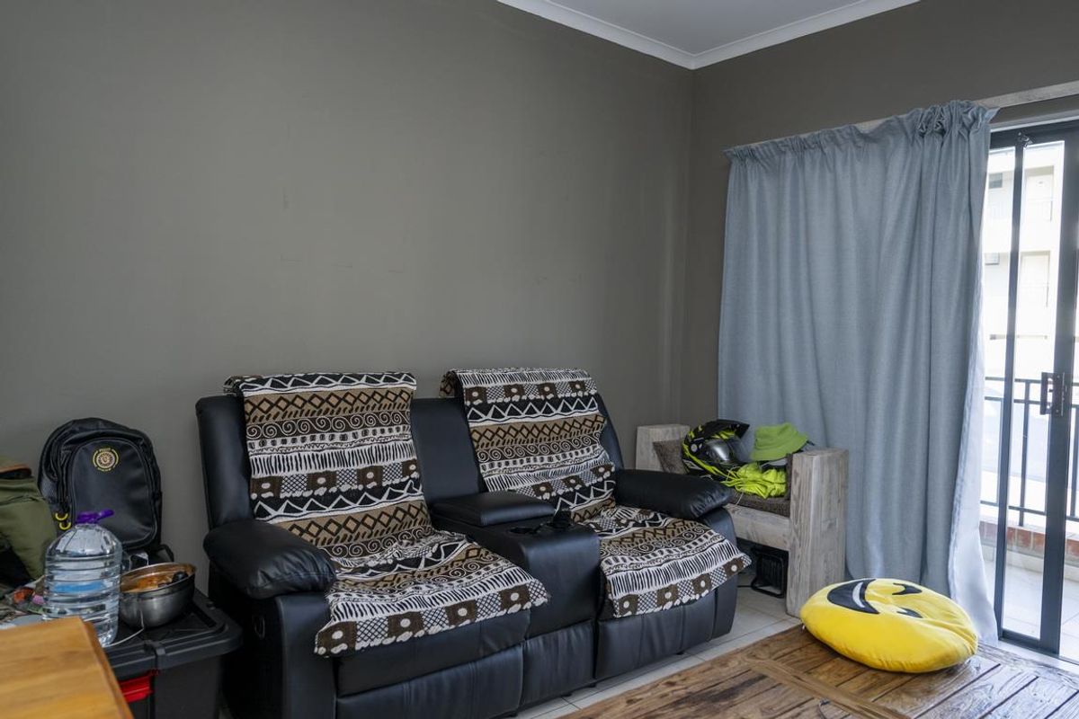 A living room area featuring tiled flooring and a sliding glass door providing access to an attached balcony.