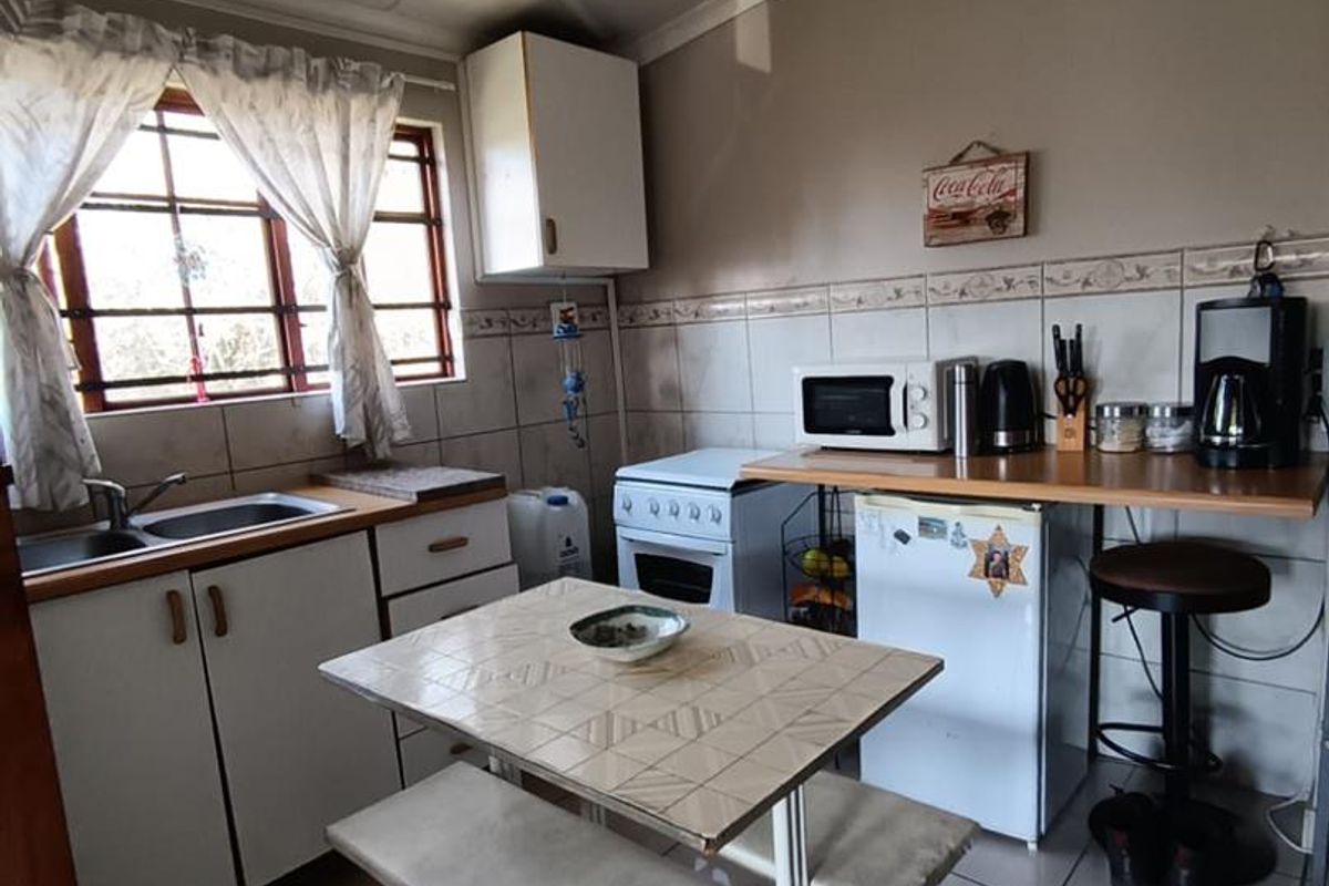 A functional kitchen featuring tiled flooring, built-in cabinetry, a double sink, and a freestanding stove, offering a practical layout for daily meal preparation.