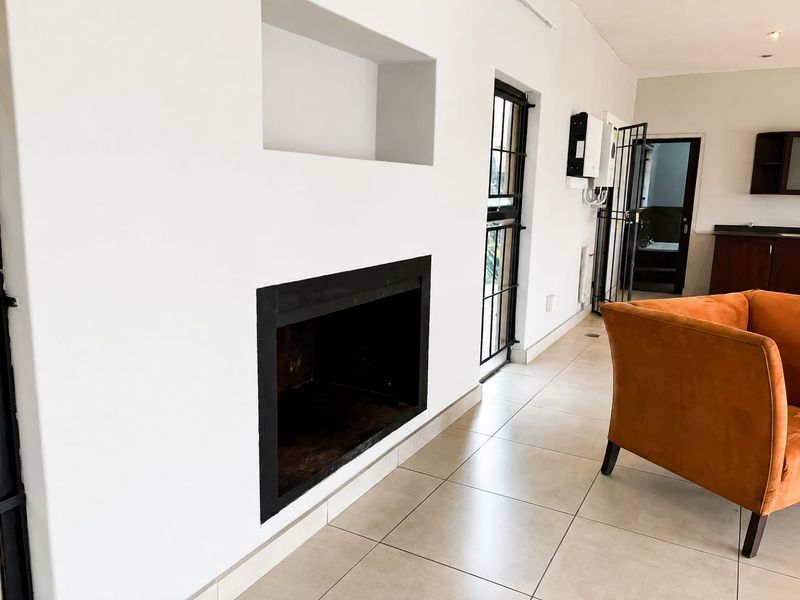 Living area featuring a built-in fireplace, recessed wall niche, and neutral tiled flooring, with direct access to an adjacent room.