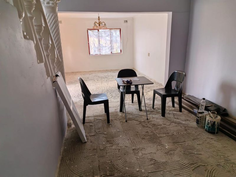 An empty living area featuring a staircase balustrade and unfinished flooring, currently undergoing renovation.