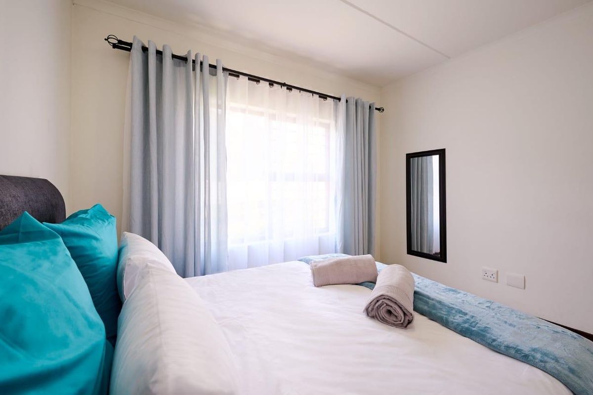 A bright and well-maintained bedroom featuring neutral walls, a window with curtain rod, and electrical outlets.